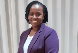 Photo of smiling woman standing against a curtain background.