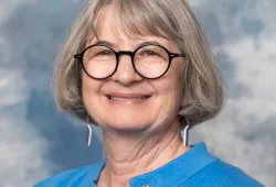 Portrait photo of woman wearing glasses and blue jacket