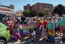 Photo of large group of people wearing rainbow colours 