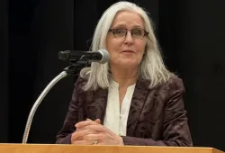 photo of woman wearing glasses speaking from a podium