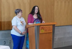 Two women standing at a lectern, delivering remarks