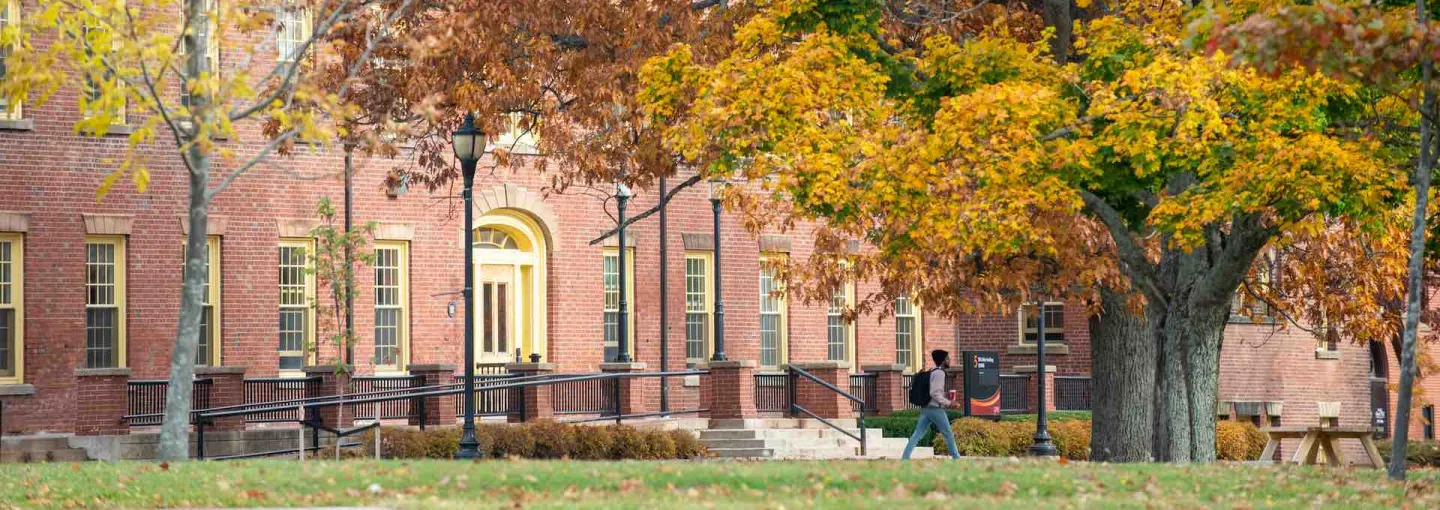 a student walking past SDU Main Building in fall