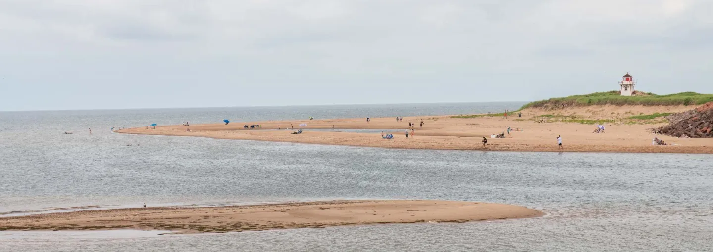 a beach with a lighthouse on the right