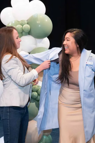 a person helping another person put on a blue lab coat