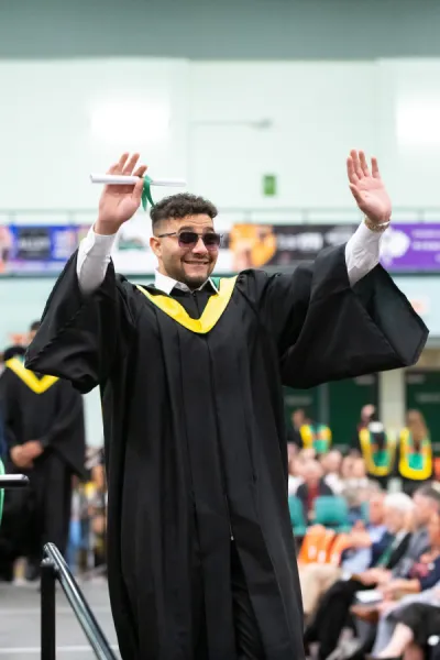a graduate raising his arms in celebration
