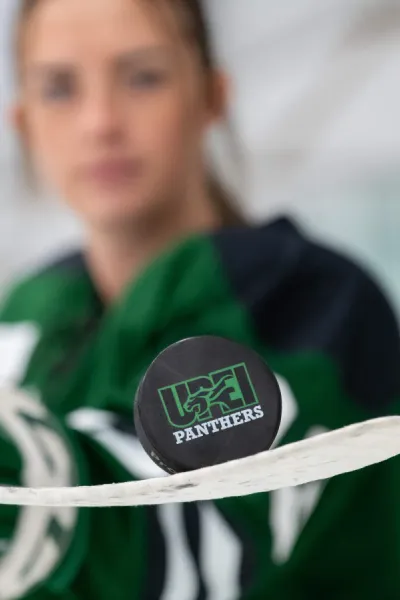 a UPEI Panthers hockey puck on a stick blade