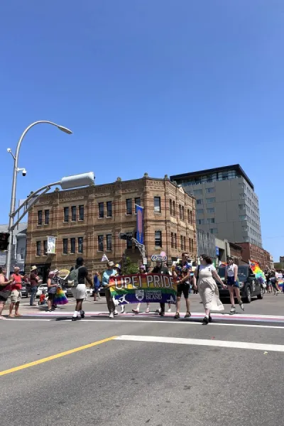 two people holding a Progress Pride flag with UPEI Pride on it