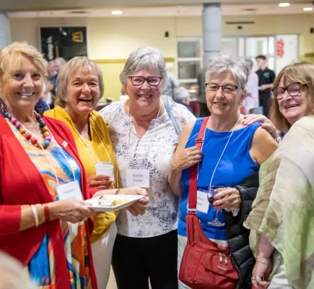 five women smiling for a photo at an alumni function