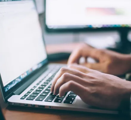 two hands typing on a laptop keyboard