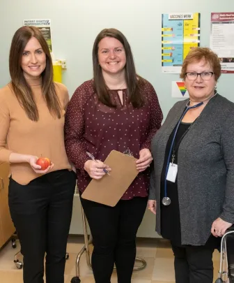 three health professionals standing in an examination room