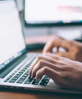 two hands typing on a laptop keyboard