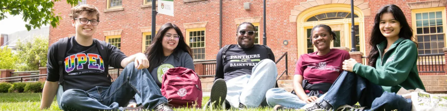 a group of students sitting in the grass in the UPEI quad