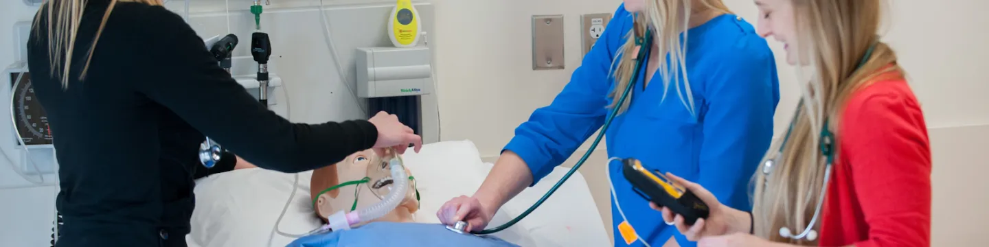 three nursing students with clinical mannequin