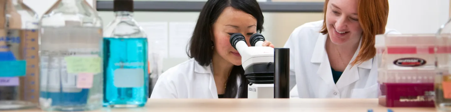 female biologists looking into microscope