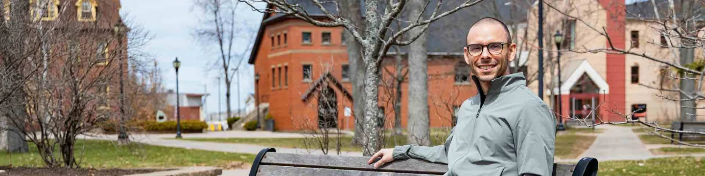 Peter Blanchard sitting on a bench in UPEI's quad