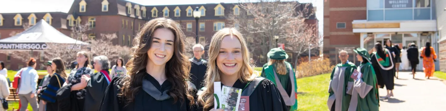 two graduates with crowd in background