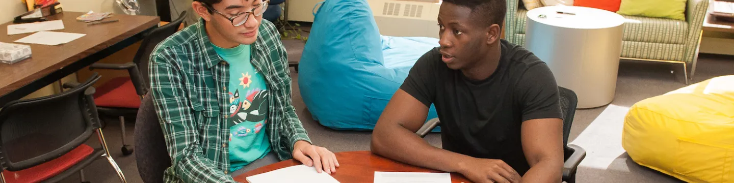 students sit at a desk writing