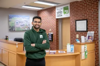 a UPEI student in a green UPEISU hoodie standing in an office