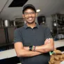 a smiling man standing in a restaurant kitchen