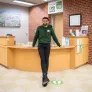 a UPEI student in a green UPEISU hoodie standing in an office