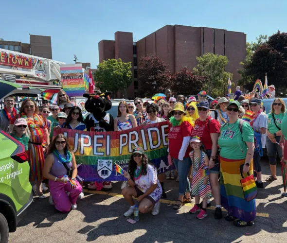 Group of people wearing colourful clothing and carrying Pride