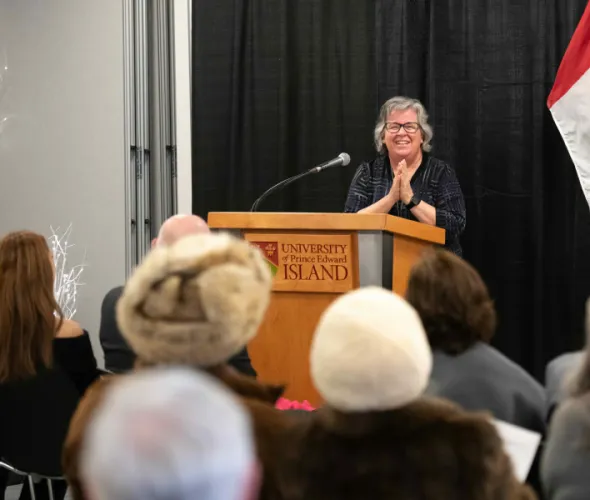 Woman standing at podium with hands clasped