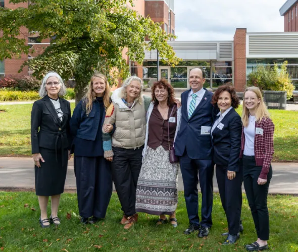 Photo of group of people standing outside in front of a brick building