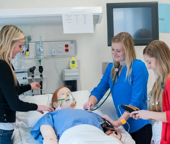 three nursing students with clinical mannequin